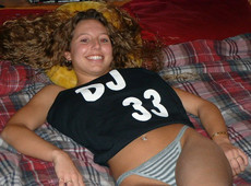 Curly playful teen sitting on bed after